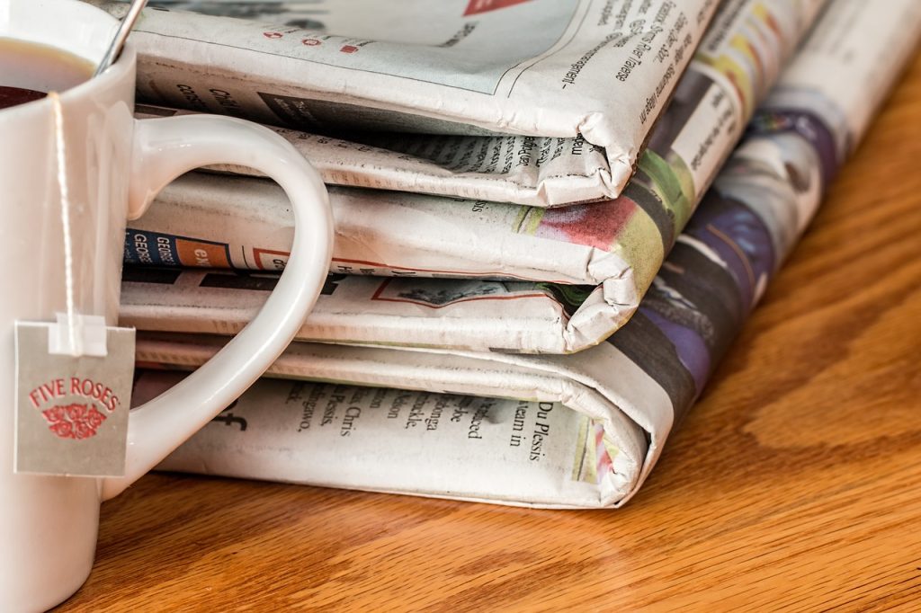 Newspapers beside a cup of tea