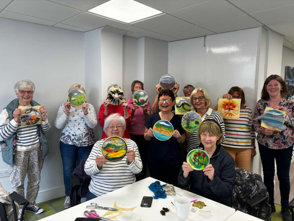 Craft group holding up their wool felting work